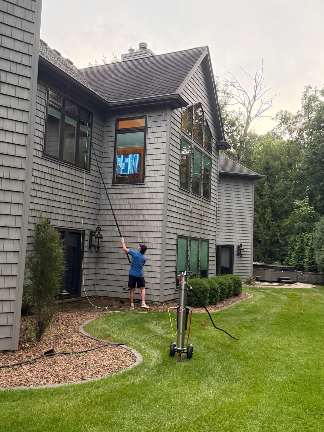 Spotless Wash technician cleaning tall home windows with an extended water-fed pole