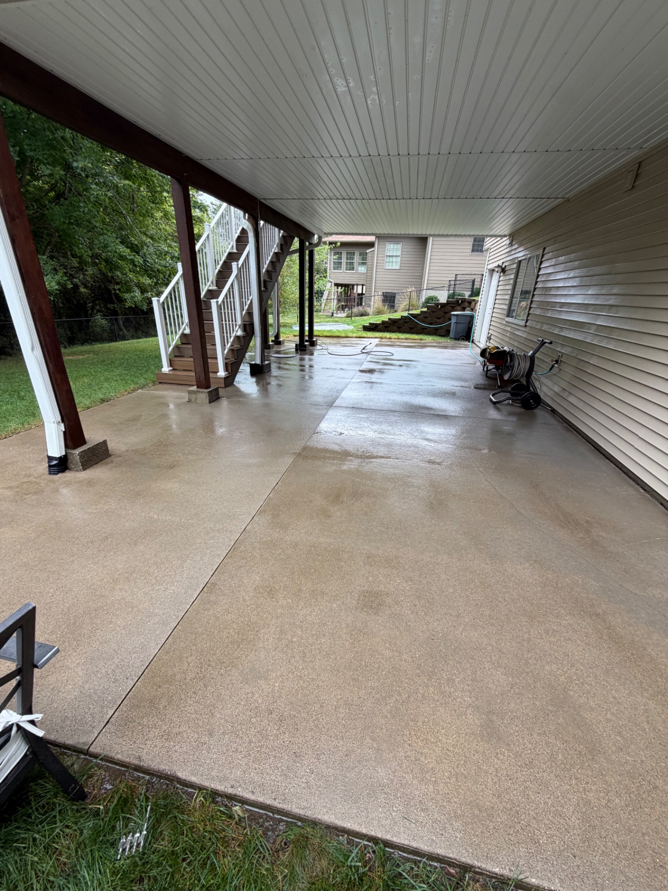 Clean concrete patio beneath a deck after pressure washing