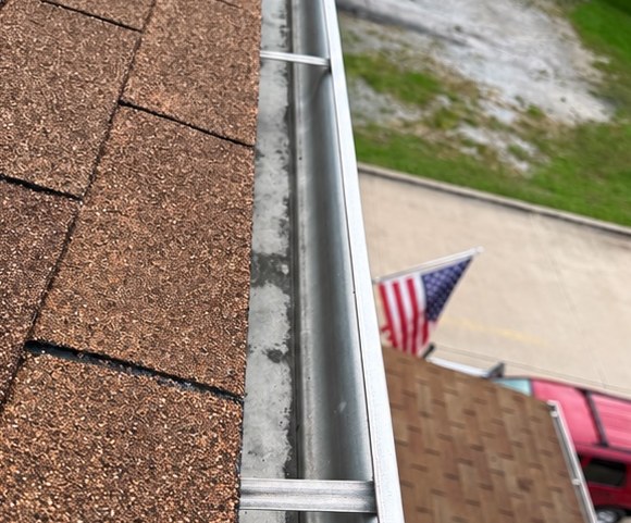 Cleared gutter along a shingle roofline after cleaning