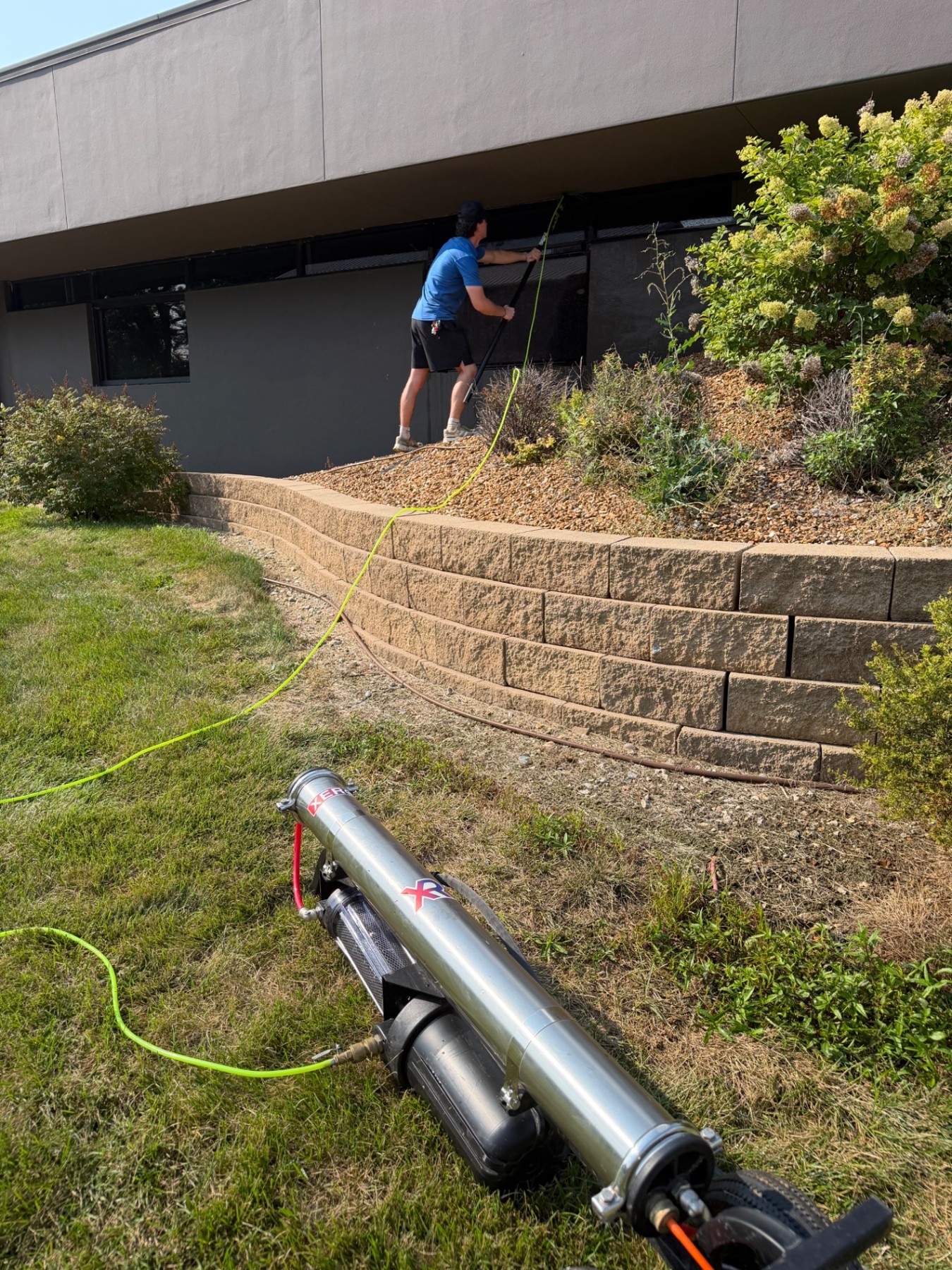Spotless Wash technician cleaning commercial windows with a water-fed pole