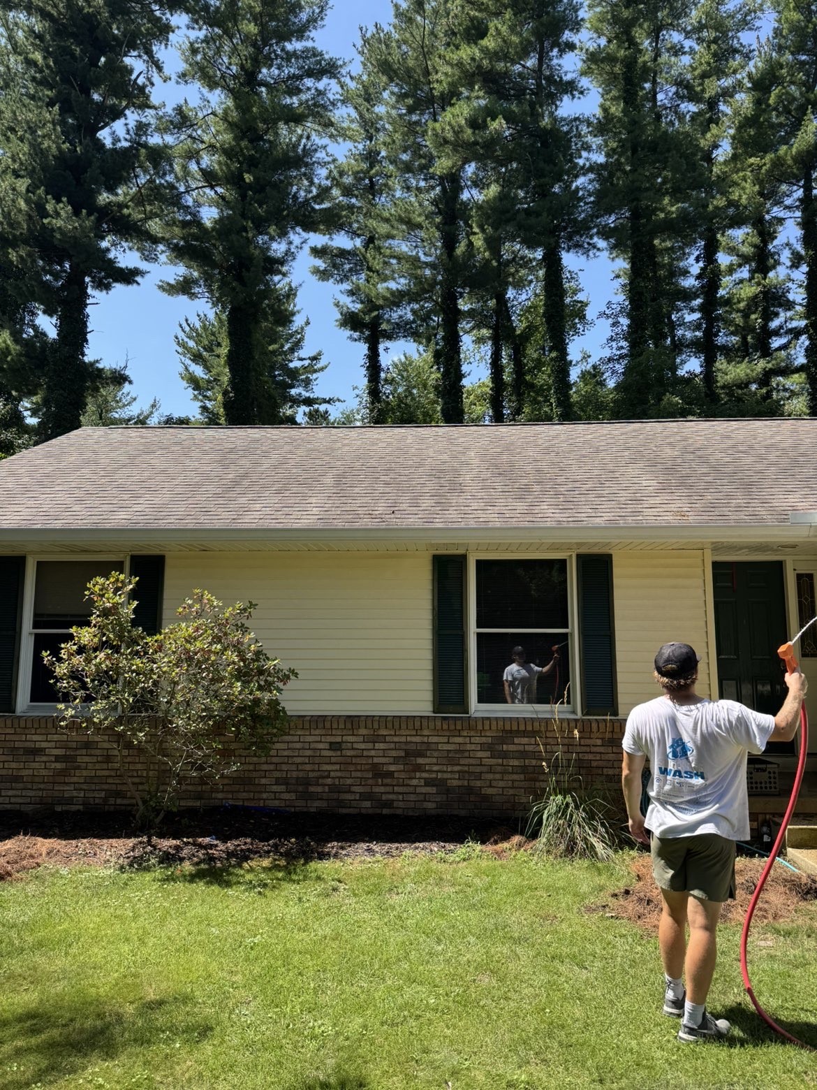 Spotless Wash technician washing the exterior of a ranch-style home